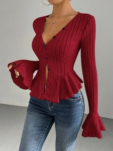 Detail of red V-neck knit top featuring ruffled hem and sleeve cuffs with black buttons
