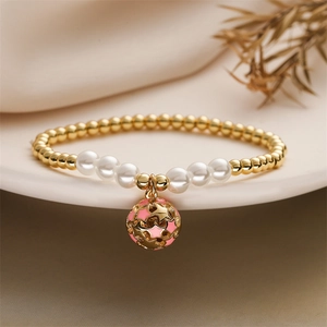 Détail du bracelet avec perles dorées, perles blanches et pendentif étoile rose