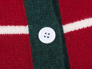 Close-up of a red knit sweater showing a white button and green stripe texture