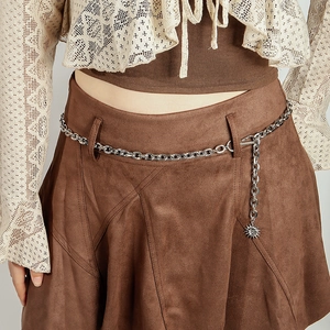 Silver metal chain belt with a sun pendant detail shown on a brown suede skirt