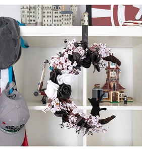 Detail of moon-shaped Halloween wreath with black roses, white flowers, and cat silhouette