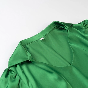 Detail view of the V-neck lapel and satin texture on this green short-sleeved top