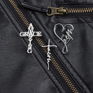 Detail view of silver Amazing Grace and Faith cross brooches on black leather jacket