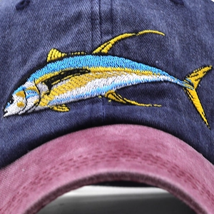 Close-up of premium fish embroidery on navy and burgundy washed cotton baseball cap