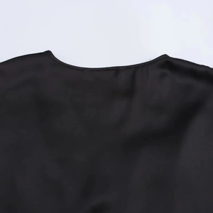 Detailansicht des Rundhalsausschnitts und der Satinstruktur dieses schwarzen Midikleides