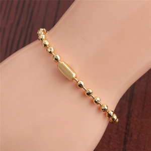 Gros plan d'un bracelet à billes dorées à facettes avec pièce centrale ovale