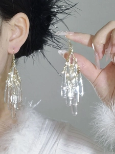Macro shot of long crystal tassel earrings with gold hardware and sparkling diamond details