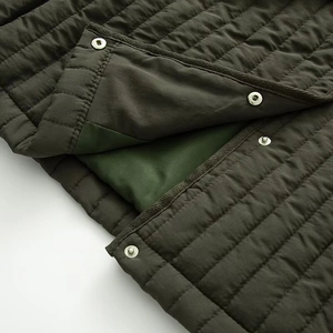 Detailed close-up of dark olive quilted jacket featuring silver metal snap buttons