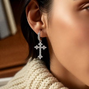 Close-up of silver zircon cross pendant hoop earrings worn by a model in lifestyle setting