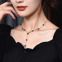 Close-up of a Y-shaped gold chain necklace with dark gray beads worn by a female model