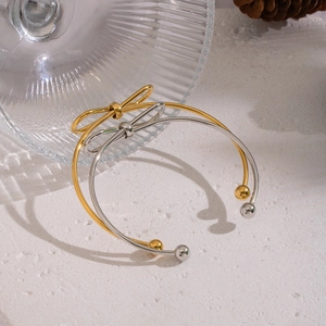 Macro detail of minimalist bow knot open bracelets in polished gold and silver finishes