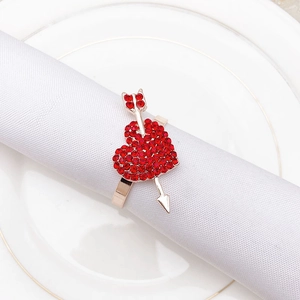 Detail of red rhinestone heart and gold arrow napkin ring on a white napkin