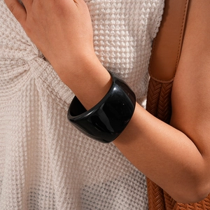 Close-up of chunky black resin bangle with glossy finish on model's wrist