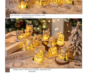 Macro detail of lighted resin Christmas house ornaments with warm LED glow and snow textures