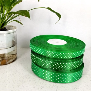 Three rolls of green grosgrain ribbon with white polka dots for gift wrapping and DIY bows