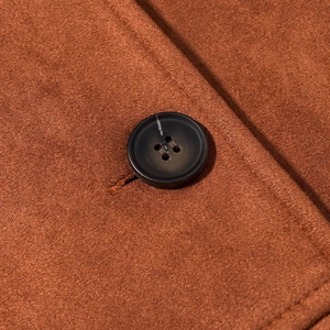 Close-up of brown suede fabric texture with a classic four-hole button and stitching
