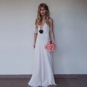 Detail of white deep V-neck maxi dress featuring a black 3D floral waist embellishment