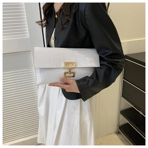 Detail view of white crocodile pattern envelope clutch featuring a golden metal lock buckle
