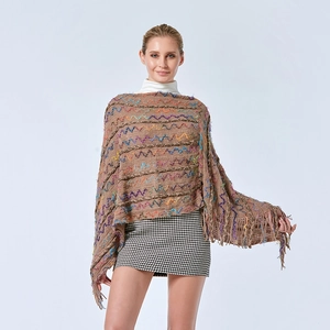 Détail d'un châle en tricot bohème avec motifs ondulés colorés et pompons à franges