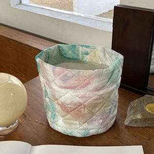 Quilted fabric organizer basket with watercolor floral pattern for makeup storage on desk