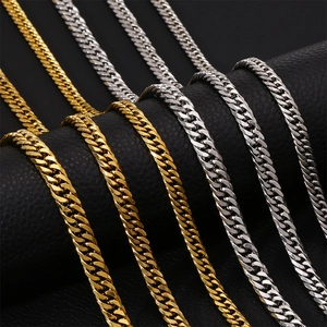 Close-up of intertwined gold and silver Cuban link necklaces on black leather background