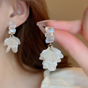 Detail of elegant gold-plated floral tassel earrings with shell petals and crystals