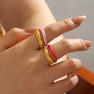 Stackable gold textured rings with pink enamel glaze details on model hand