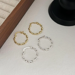 Macro shot of twisted 925 sterling silver hoop earrings in gold and silver finishes