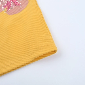 Dettaglio ravvicinato del tessuto a costine giallo con fiore di strass rosa e cuciture