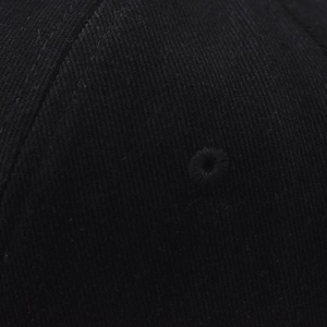 Macro detail of breathable embroidered eyelet on black cotton twill baseball cap