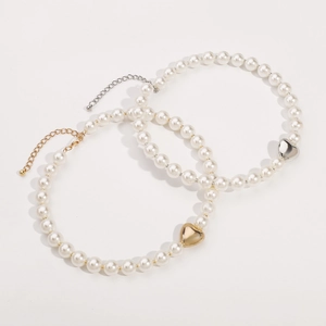 Elegant pearl necklace with gold and silver heart pendants on a clean white background
