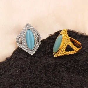 Detail of adjustable gold and silver rings with oval light blue gemstone and beadwork