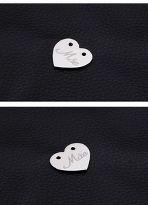 Close-up of heart-shaped stainless steel charms with Mae engraving on leather texture