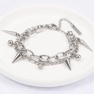 Double-layered silver punk bracelet with metal spikes and sphere charms on a white tray