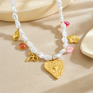 Elegant pearl necklace with gold heart flower pendants and crystal charms in a soft setting