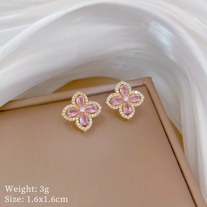 Detail of pink zircon flower earrings with dimensions 1.6x1.6cm on a silk background