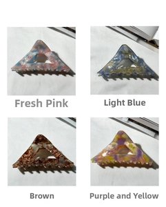 Detailed macro view of four marble-patterned triangle claw clips in assorted colors
