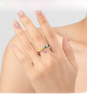 Close-up of colorful beaded ring featuring a sweet flower pendant on a model's finger