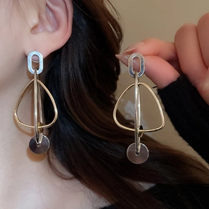 Détail de boucles d'oreilles géométriques avec finition en métal bicolore or et argent
