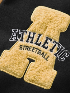 Vue macro d'une broderie lettre A jaune sur tissu noir avec texte Athletic et Streetball
