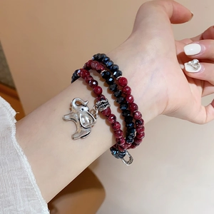 Macro shot of a silver elephant charm on a layered red and black beaded bracelet