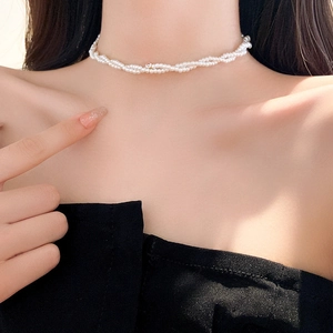 Detail view of a layered pearl choker necklace with a center zircon on a female model