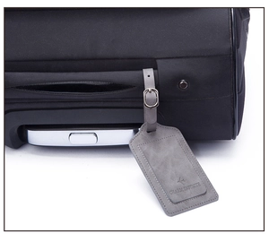 Grey PU leather luggage tag with airplane icon attached to a black suitcase handle