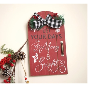 Macro view of red wooden Christmas sled sign with Merry & Bright text and pine details
