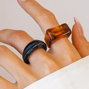 Close-up of minimalist acrylic rings featuring black marble and amber resin textures
