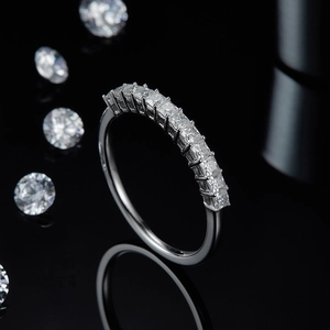 Macro shot of silver moissanite band ring with square-cut stones and mirrored reflection