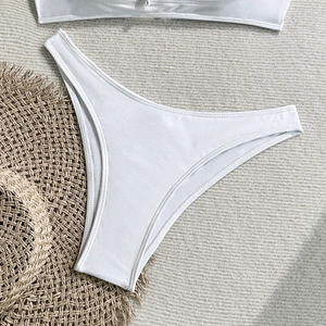 Flat lay of white high-quality bikini bottoms with ribbed texture on a beige summer mat