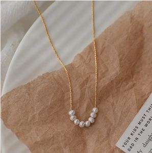 Elegant gold titanium steel necklace featuring seven white mini pearls in a curved design