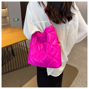 Dettaglio borsa shopper trapuntata fucsia con catena dorata indossata su camicia