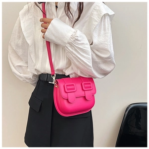 Detail of fuchsia saddle bag with dual metal buckles on white ruffle shirt